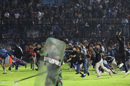 Aficionados al fútbol corren durante una serie de enfrentamientos en Malang, Indonesia, el sábado 1 de octubre de 2022 (AP Foto/Yudha Prabowo)