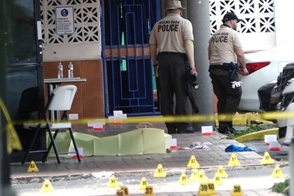 Agentes de la policía de Miami-Dade inspeccionan el exterior de un salón de fiestas que fue atacado a tiros desde afuera cerca de Hialeah, Florida, el domingo 30 de mayo de 2021. (AP Foto/Lynne Sladky)