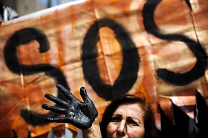 ARCHIVE - Una activista con la mano pintada de negro como símbolo de la contaminación de petróleo participa en una performance de protesta para exigir medidas de prevención a los derrames de crudo, a las afueras de la petrolera estatal en Lima, Perú, el lunes 22 de agosto de 2016. Líderes indígenas anunciaron el jueves 10 de noviembre de 2022 que se reunirán con grandes bancos de inversión para advertirles de no financiar nuevos proyectos de la empresa nacional de petróleo de Perú, Petroperú, hasta que ofrezca una solución para remediar la contaminación petrolera en la Amazonía. (AP Foto/Rodrigo Abd, Archivo)