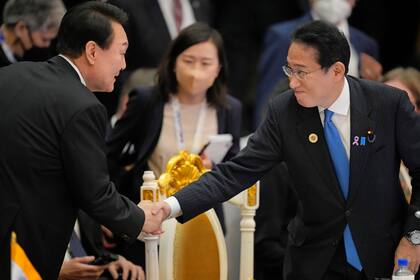 ARCHIVO - El primer ministro japonés Fumio Kishida, derecha, estrecha la mano del presidente surcoreano Yoon Suk Yeol durante la cumbre de ASEAN en Phnom Penh, Camboya, 13 de noviembre de 2022. (AP Foto/Vincent Thian, File)