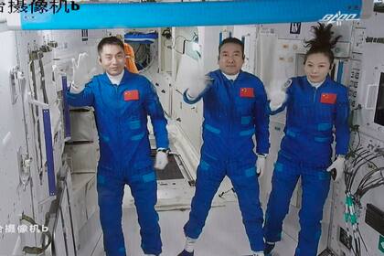 ARCHIVO - En esta fotografía facilitada por la agencia de noticias Xinhua y tomada de una imagen de video en el Centro de Control Aeroespacial de Beijing el 16 de octubre de 2021, se ve a los astronautas chinos Ye Guanfgu (izquierda) y Zhai Zhigang (centro), y a la astronauta Wang Yaping (derecha) que saludan tras su ingreso en el módulo central de la estación espacial de China. (Tian Dingyu/Xinhua vía AP, archivo)