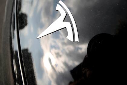 Archivo - Fotografía del 8 de julio de 2018 de nubes reflejadas sobre el logotipo de Tesla en el capó de un vehículo de la marca afuera de una sala de exposición en Littleton, Colorado. (AP Foto/David Zalubowski, Archivo)