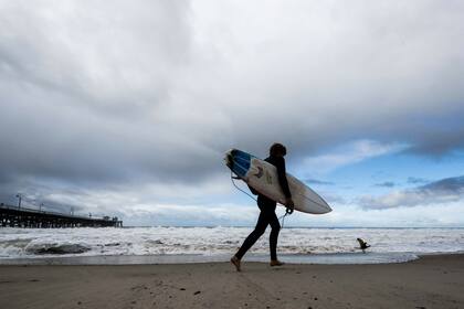ARCHIVO - Un surfista se encamina hacia el agua mientras una tormenta se desplaza por el área, el 12 de diciembre de 2022, en San Clemente, California. (Paul Bersebach/The Orange County Register vía AP, archivo)