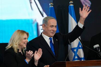 Benjamin Netanyahu, ex primer ministro israelí y líder del partido Likud, acompañado por su esposa Sara, saluda a sus simpatizantes después de conocerse los primeros resultados de los comicios parlamentarios, el miércoles 2 de noviembre de 2022, en Jerusalén. (AP Foto/Tsafrir Abayov)