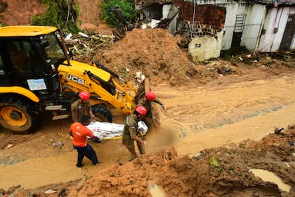 Bomberos retiran un cuerpo recuperado de un deslave provocado por las fuertes lluvias en el vecindario de Jardim Monte Verde, el domingo 29 de mayo de 2022, en Recife, en el estado de Pernambuco, Brasil. (AP Foto/Joao Carlos Mazella)
