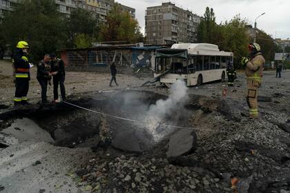 Bomberos y agentes de la policía trabajan en el sitio donde una explosión creó un cráter en una calle tras un ataque ruso en Dnipro, Ucrania, el lunes 10 de octubre de 2022. (AP Foto/Leo Correa)