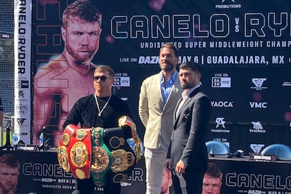 Canelo Alvarez sostiene su colección de cinturones de campeón de peso medio frente al retador John Ryder en la conferencia de prensa en San Diego el jueves 15 de marzo del 2023 previo al combate en Guadalajara el 6 de mayo. (AP Foto/Greg Beacham)