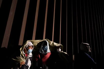 Cuatro cubanos intentan mantenerse calientes después de cruzar la frontera desde México y entregarse a las autoridades para solicitar asilo, el 3 de noviembre de 2022, cerca de Yuma, Arizona. (AP Foto/Gregory Bull, Archivo)