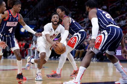 Darius Garland, base de los Cavaliers de Cleveland, se cuela entre Jalen Green (4) y TyTy Washington Jr., de los Rockets de Houston, en el duelo del jueves 26 de enero de 2023 (AP Foto/Michael Wyke)