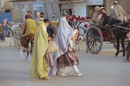 Dos mujeres afganas con sus hijos caminan usando una burka en una calle concurrida en Afganistán, en 1996, bajo el anterior régimen talibán