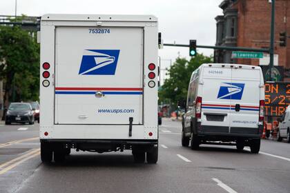 Dos vehículos del Servicio Postal de Estados Unidos avanzan por una calle  (AP Foto/David Zalubowski, Archivo)