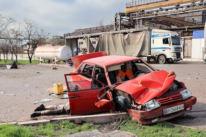 El cuerpo de un civil se ve junto a un auto dañado cerca de la Planta Metalúrgica Ilich de Acero y Hierro, la segunda instalación metalúrgica más grande de Ucrania, en una zona contolad por fuerzas separatistas con apoyo ruso en Mariúpol, Ucrania, el sábado 16 de abril de 2022. (AP Foto/Alexei Alexandrov)