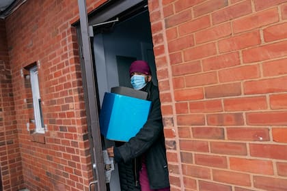 El doctor Eugenio Fernández transporta una caja con vacunas de Moderna para combatir el COVID-19, que llevará de su farmacia a una escuela secundaria donde funciona un centro de vacunaciones en Central Falls, Rhode Island, el 20 de febrero del 2021. (AP Photo/David Goldman)