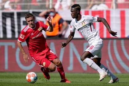 El jugador del Union de Berlín Max Kruse, izquierda, se disputa el balón con Odilon Kossounou, de Leverkusen, en un partido de la Bundesliga alemana el sábado, 14 de agosto del 2021. El encuentro terminó 1-1.  (AP Foto/Michael Sohn)