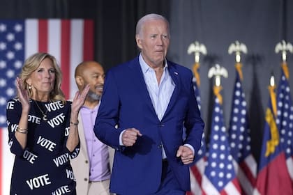 El presidente Joe Biden, derecha, y la primera dama Jill Biden, izquierda, caminan hacia el escenario para hablar en un mitin de campaña, acompañados al fondo por Eric Fitts, el viernes 28 de junio de 2024, en Raleigh, Carolina del Norte