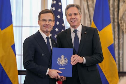 El secretario de Estado, Antony Blinken, a la derecha, junto al primer ministro sueco, Ulf Kristersson, sostienen los instrumentos de adhesión de Suecia a la OTAN en la sala Benjamin Franklin del Departamento de Estado, en Washington. (AP Photo/Jess Rapfogel)