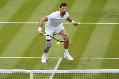 El serbio Novak Djokovic se entrena en una de las canchas de Wimbledon con un vendaje especial en su rodilla derecha tras su operación de menisco