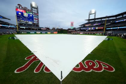 El terreno de juego es cubierto por la lona ante la amenaza de lluvia previo al tercer juego de la Serie Mundial entre los Astros de Houston y los Filis de Filadelfia, el lunes 31 de octubre de 2022. (AP Foto/Matt Slocum)