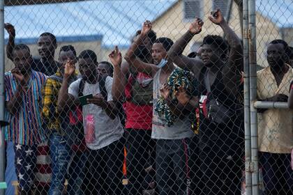 En esta fotografía del 5 de agosto de 2021, los migrantes --mayormente haitianos-- se paran detrás de una cerca de alambre en un campamento mientras ven a otros migrantes subir a un autobús que los llevará a otro lado del país, cerca de la frontera con Costa Rica, en San Vicente, provincia de Darién, Panamá, cerca de la frontera con Colombia. La canciller panameña Erika Mouynes dijo el lunes 20 de septiembre a la AP que Panamá solicitará ayuda internacional durante la Asamblea General de las Naciones Unidas para atender ese masivo flujo irregular. (Foto AP/Arnulfo Franco, Archivo)