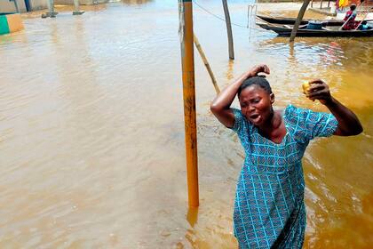 En esta imagen difundida por la Agencia Nacional para el Manejo de Emergencias, una mujer llora mientras transita por una calle inundada tras un naufragio, el viernes 7 de octubre de 2022, en Anambra, Nigeria. (National Emergency Management Agency via AP)