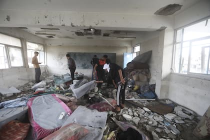 Los palestinos observan las secuelas del ataque israelí a una escuela administrada por la ONU que mató a decenas de personas en el campo de refugiados de Nusseirat en la Franja de Gaza, el jueves 6 de junio de 2024