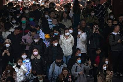Gente, algunos con mascarilla, visitan el Templo del Cielo en Beijing, 26 de febrero de 2023. China dice que ha sido “abierta y transparente” en la búsqueda de los orígenes de la pandemia de COVID-19 y rechaza las críticas de Estados Unidos por politizar el asunto. (AP Foto/Andy Wong)