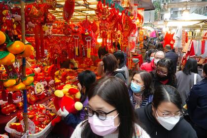 Gente caminando junto a decoraciones del Año Nuevo Lunar en un mercado en Hong Kong, el lunes 31 de enero de 2022, víspera del Año Nuevo Lunar. (AP Foto/Vincent Yu)