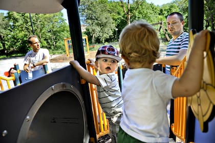 Henrik Holgersson, a la derecha, observa a su hijo, Arvid, en el centro con sombrero, jugar con Walter Johansson acompañado por su padre Henrik Johansson en un parque infantil en Estocolmo, Suecia, el miércoles 29 de junio de 2011
