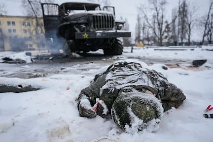 El cuerpo de un militar está cubierto de nieve junto a un vehículo militar ruso lanzacohetes múltiple destruido en las afueras de Kharkiv, Ucrania, el viernes 25 de febrero de 2022.