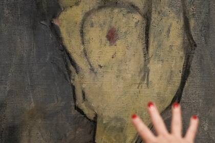 Inna Berkowits, historiadora del arte en el Museo Hecht de la Universidad de Haifa, explica detalles de la pintura de Amadeo Modigliani "Desnuda con sombrero", que cuelga boca abajo porque hay otra pintura del artista, "Maud Abrantes", en el reverso del mismo lienzo, el 28 de junio de 2022 en Haifa, Israel. Los curadores del museo descubrieron tres bocetos previamente desconocidos del célebre artista del siglo XX ocultos bajo la superficie de la pintura, utilizando tecnología de rayos X. (Foto AP/Ariel Schalit)