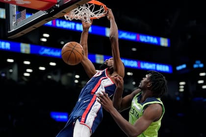 Kevin Durant, de los Nets de Brooklyn, anota de volcada frente a Anthony Edwards, de los Timberwolves de Minnesota, en la segunda mitad del partido de la NBA en Nueva York, el viernes 3 de diciembre de 2021. (AP Foto/Mary Altaffer)