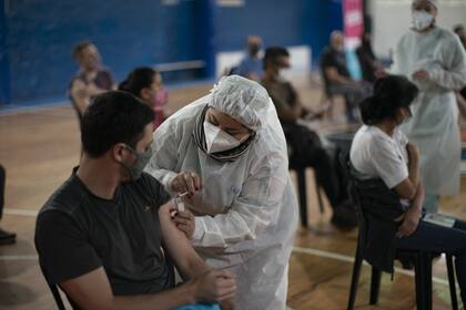 La supervisora de enfermera Paola Almiron inocula a un hombre con una dosis de la vacuna de Sinopharm contra el COVID-19 en un gimnasio en las afueras de Buenos Aires, el viernes 9 de julio de 2021