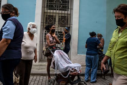 Las personas usan máscaras para frenar la propagación del COVID-19 mientras esperan su turno para comprar en una tienda estatal en La Habana, Cuba, el miércoles 16 de febrero de 2022. (AP Foto/Ramón Espinosa)