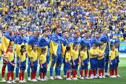 Los jugadores de Ucrania envueltos en banderas de su país, antes del partido contra Rumania