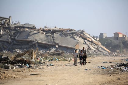 Los palestinos pasan junto a los edificios destruidos del campamento de al-Bureij en el centro de la Franja de Gaza el 2 de junio de 2024, en medio del conflicto en curso entre Israel y el grupo militante palestino Hamas.