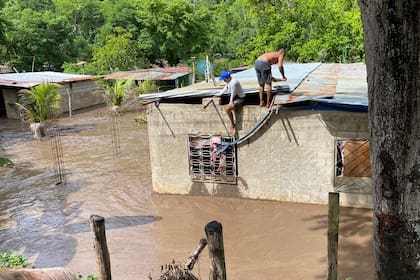 Los residentes reparan el techo de su casa inundada después de que un río se creciera debido a las fuertes lluvias tras el paso del huracán Beryl en la carretera de Cumaná a Cumanacoa, estado Sucre, Venezuela, el 2 de julio de 2024.