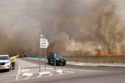 Los vehículos abandonan un área envuelta por el humo de los incendios después de que cohetes lanzados desde el sur del Líbano impactaran áreas en los Altos del Golán anexados por Israel, el 4 de julio de 2024.