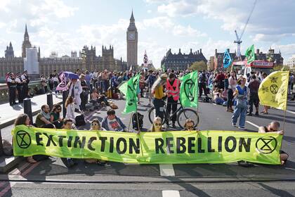 Manifestantes participan en una protesta del movimiento de acción climática Extinction Rebellion en el puente Westminster en Londres el 15 de abril del 2022.  (Stefan Rousseau/PA vía AP)