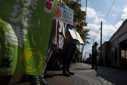 Miembros de Kodaira Solar sostienen carteles durante una manifestación para promover plantas de energía solar en la comunidad, en el exterior de la estación de tren de Kodaira, al oeste de Tokio, el 24 de septiembre de 2021. (AP Foto/Hiro Komae)