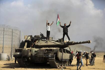 Militantes palestinos celebran victoriosos sobre un tanque israelí que pusieron fuera de combate durante la incursión del 7 de octubre