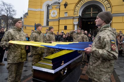 Militares ucranianos sostienen una bandera sobre el ataúd de su camarada Volodymyr Yezhov, quien murió peleando contra las fuerzas rusas, en la Catedral de San Volodymyr en Kiev, Ucrania, el 27 de diciembre de 2022. (Foto AP/Efrem Lukatsky)