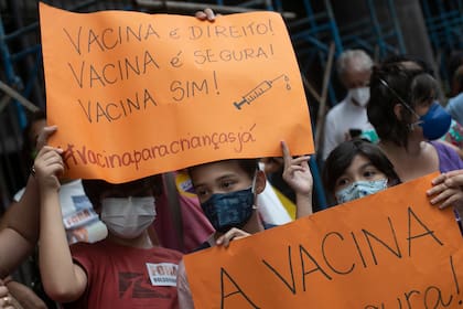 Niños sostienen letreros con el mensaje en portugués: “¡La vacuna es un derecho! ¡La vacuna es segura! ¡Sí a la vacuna!”, durante una manifestación a favor de la vacuna contra el COVID-19 en Río de Janeiro, el miércoles 5 de enero de 2022. (AP Foto/Bruna Prado)