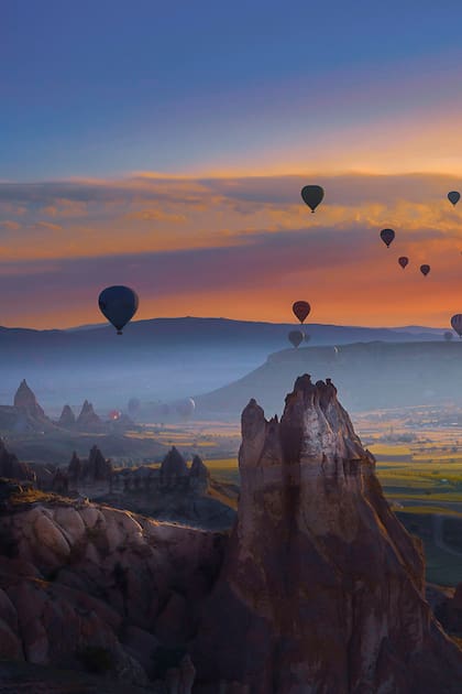 Paisaje de la fabulosa Capadocia (Kapadokya) y los coloridos globos de aire voladores en el cielo al amanecer en Anatolia