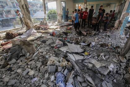 Palestinos inspeccionan los daños después de un ataque aéreo israelí contra una escuela para personas desplazadas de la ONU