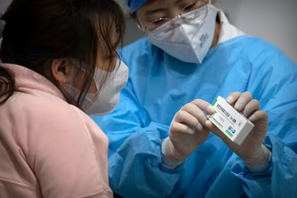 Personal médico observa una vacuna Sinopharm en un centro de vacunación en Beijing, 15 de enero de 2021. Un estudio publicado por la influyente revista médica Journal of the American Medical Association dice que dos vacunas de Sinopharm parecen ser seguras y eficaces contra el COVID-19. (AP Foto/Mark Schiefelbein)