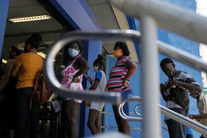 Personas hacen fila para retirar dinero de un programa de asistencia social en un banco público, el miércoles 17 de noviembre de 2021, en Río de Janeiro. (AP Foto/Silvia Izquierdo)