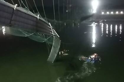 Rescatistas en botes buscan a personas en el río Machchu debajo de un puente que se vino abajo el domingo 30 de octubre de 2022, en el distrito de Morbi, India. (Foto AP/Rajesh Ambaliya)