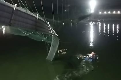 Rescatistas en botes buscan a personas en el río Machchu debajo de un puente de cable que se derrumbó en el distrito de Morbi, India, el domingo 30 de octubre de 2022. (Foto AP/Rajesh Ambaliya)