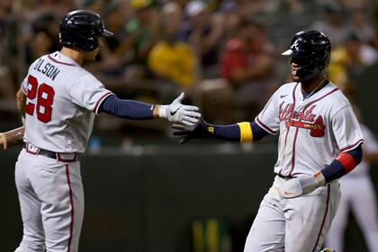 Ronald Acuna Jr. (derecha), de los Bravos de Atlanta, recibe la felicitación de Matt Olson (28) tras anotar en un elevado de sacrificio de Austin Riley en el sexto inning del juego de la MLB contra los Atléticos de Oakland, en Oakland, California, el 6 de septiembre de 2022. (AP Foto/Jed Jacobsohn)