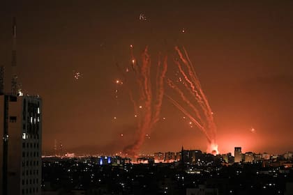 Se dispara una salva de cohetes por parte de militantes palestinos desde Gaza, mientras un misil israelí lanzado desde el sistema de misiles de defensa Iron Dome intenta interceptar los cohetes disparados desde la Franja de Gaza sobre la ciudad de Netivot en el sur de Israel el 8 de octubre de 2023.